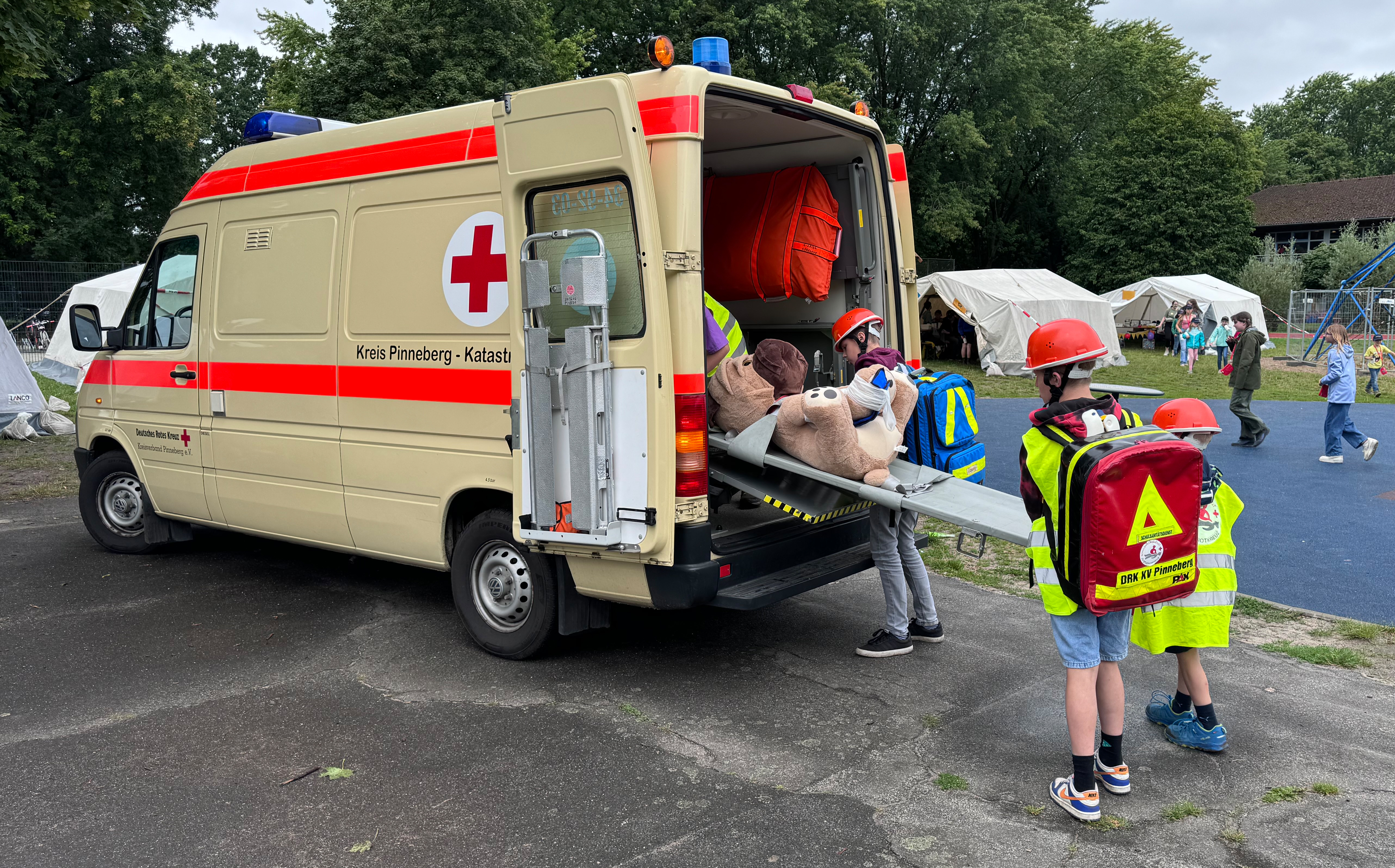 Kinder tragen Teddy zum Rettungswagen