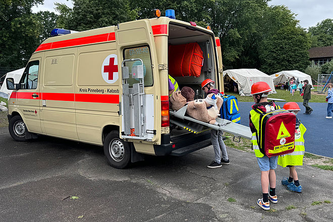 Kinder tragen Teddy zum Rettungswagen